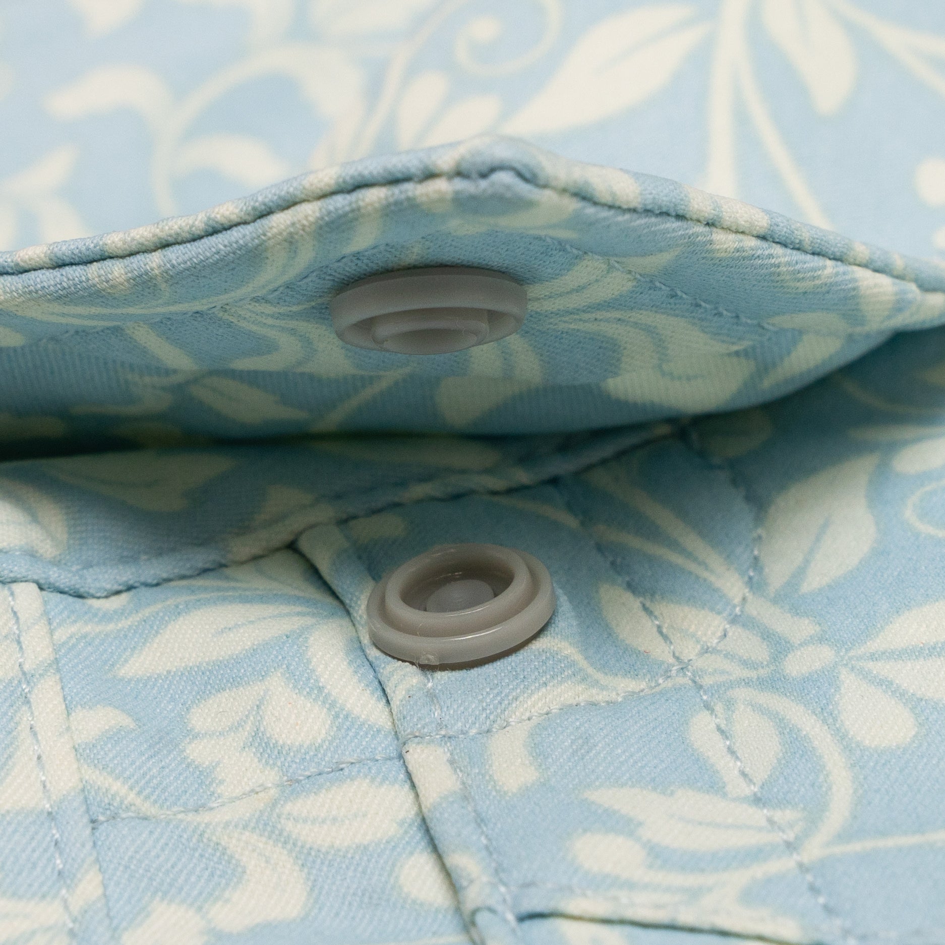 close up photo of collar button snaps on paisley blue shirt