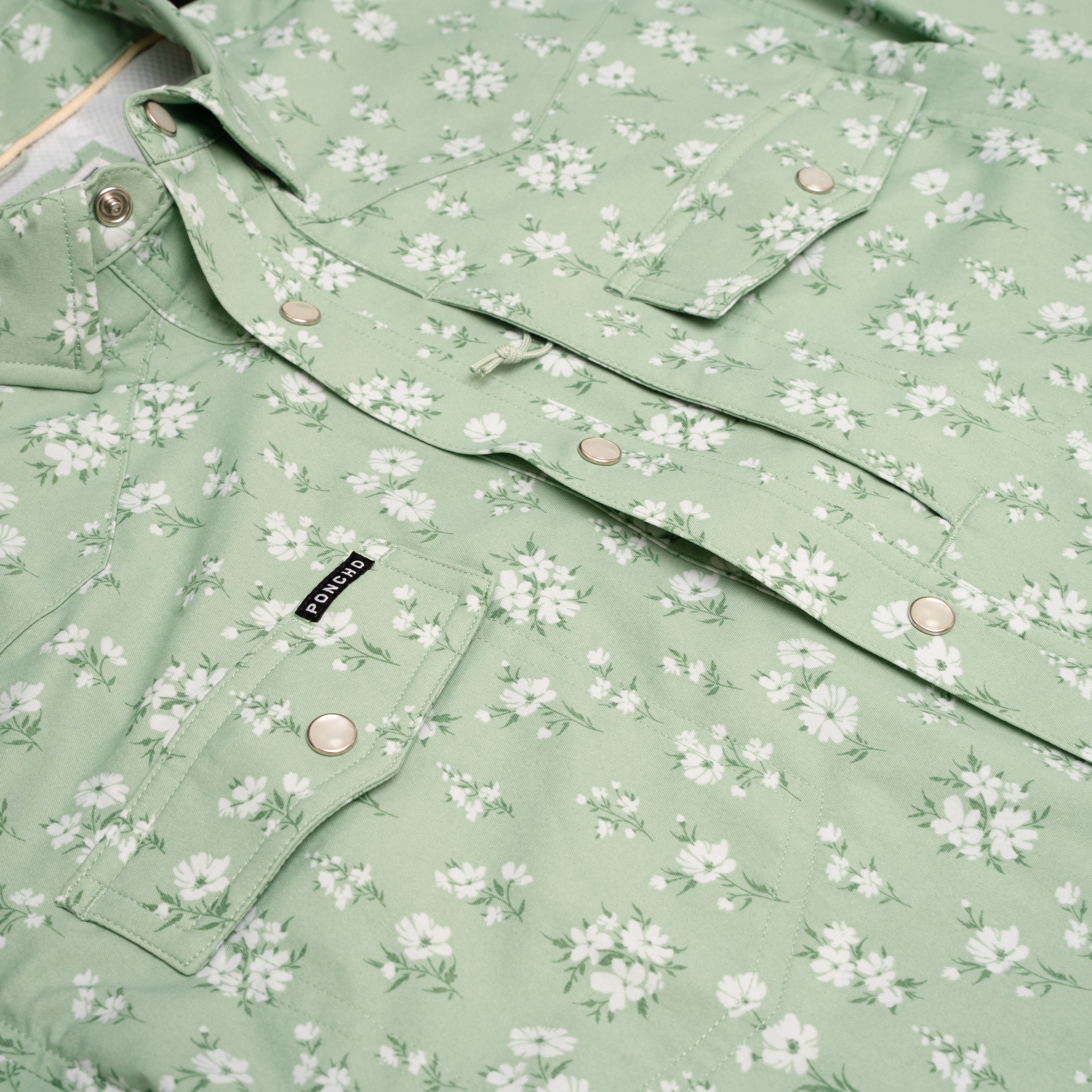 Close up photo of pearl snap buttons and floral print of green shirt