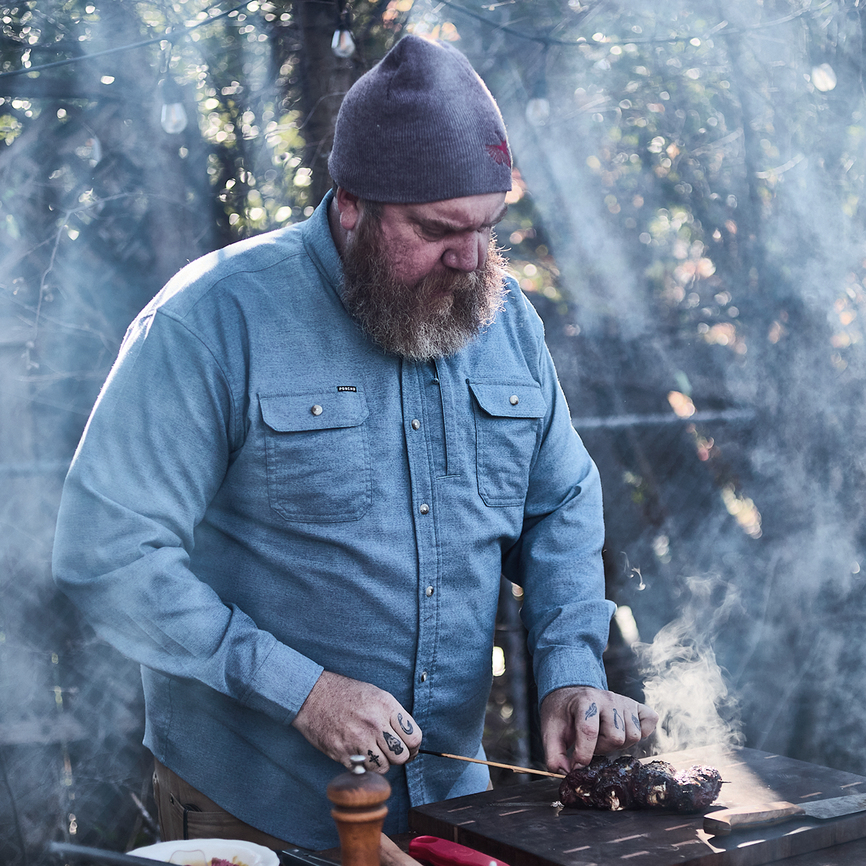 man cooking meat and sun shining through