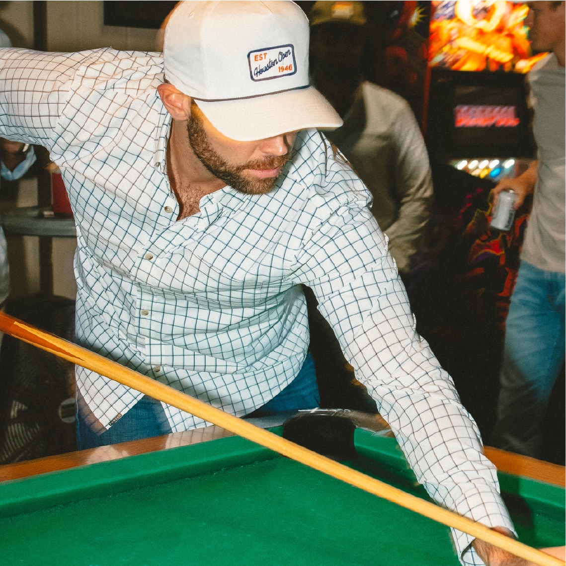 Man shooting pool in blue plaid button down shirt