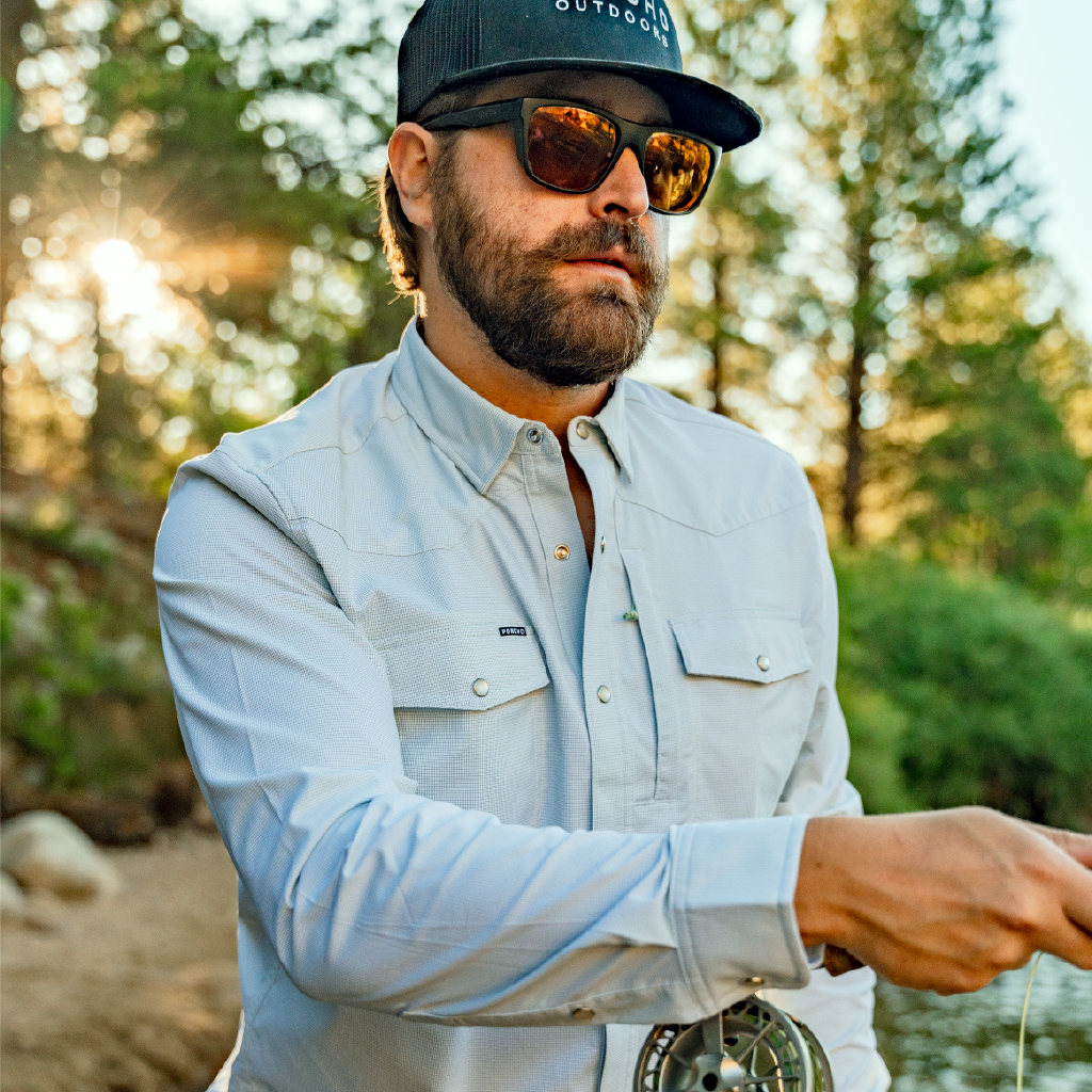 man fly fishing in long sleeve button down green micro grid