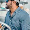 Man driving boat in slate blue button down