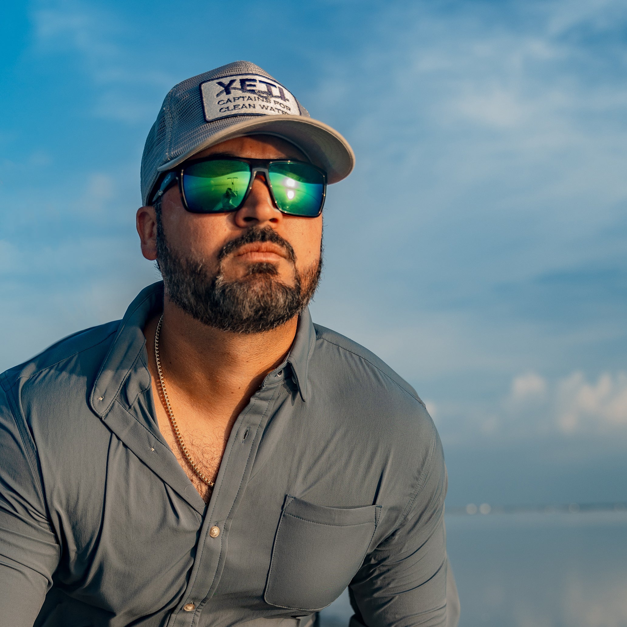 Man driving boat in slate blue button down