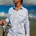 man holding a fly rod wearing a white button down fishing shirt