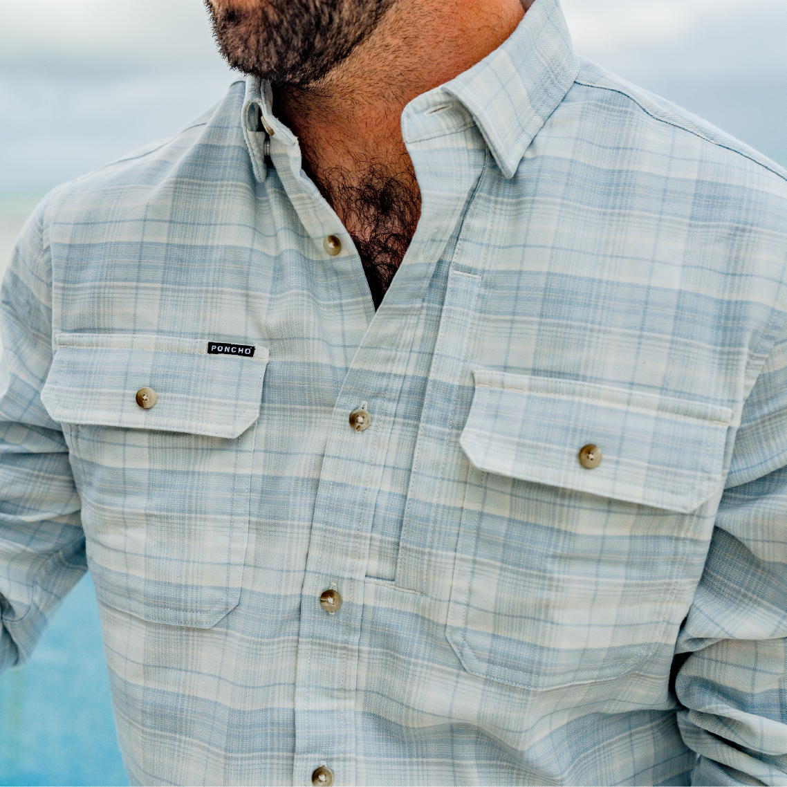 Photo of man sitting on the beach wearing a flannel shirt