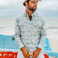 man sitting on the beach drinking a beer