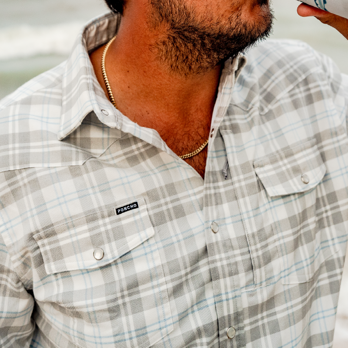 Close up photo of man wearing blue and grey plaid flannel