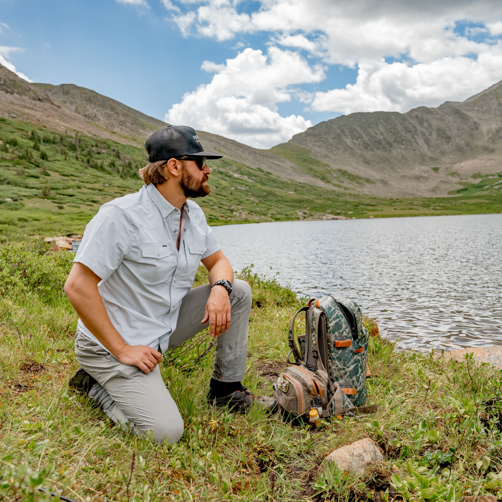 man looking over high alpine lake in green pearl snap