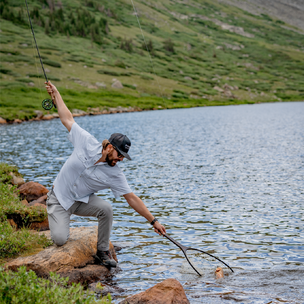 man netting fish on high alpine lake