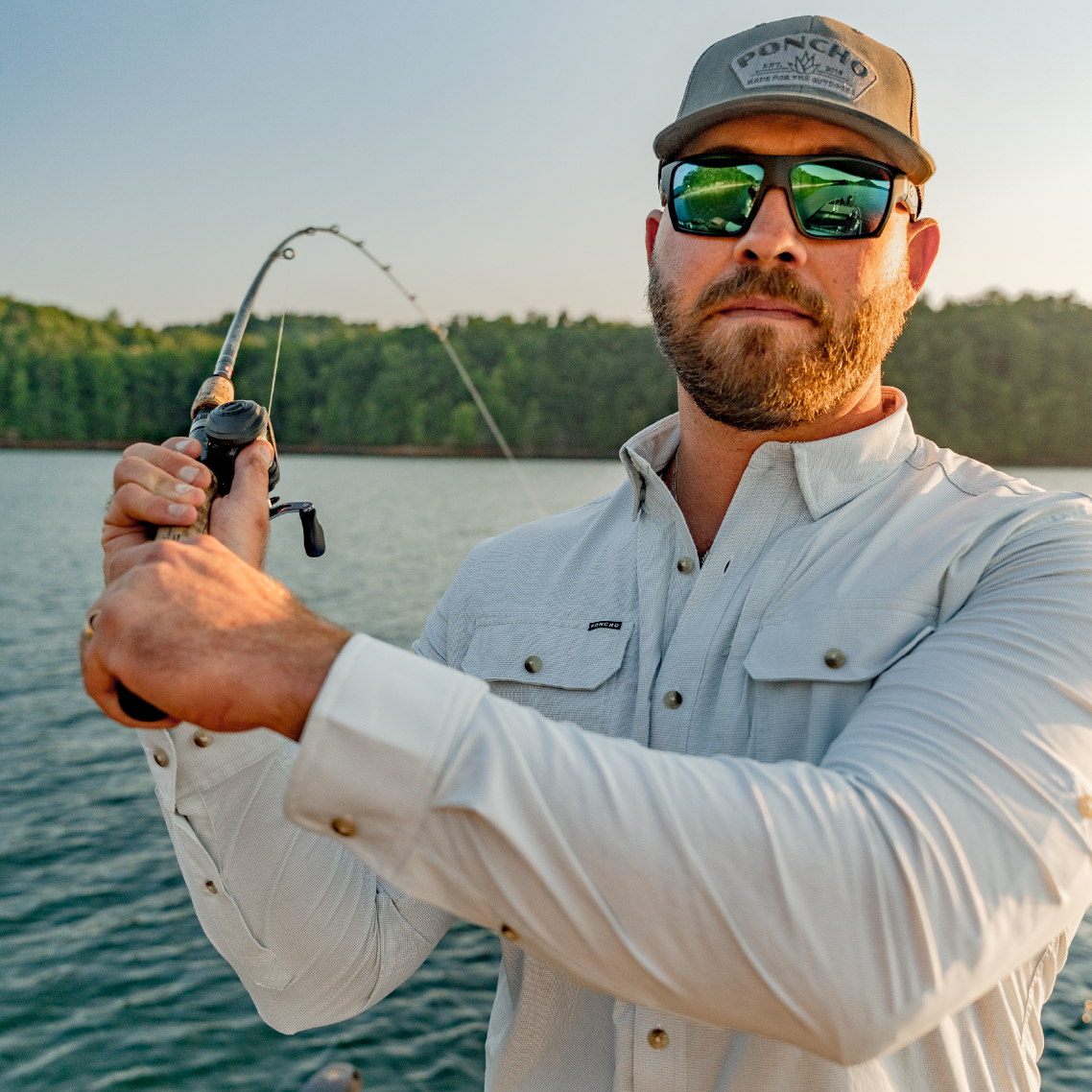 Man casting a fishing rod while wearing a long sleeve green shirt