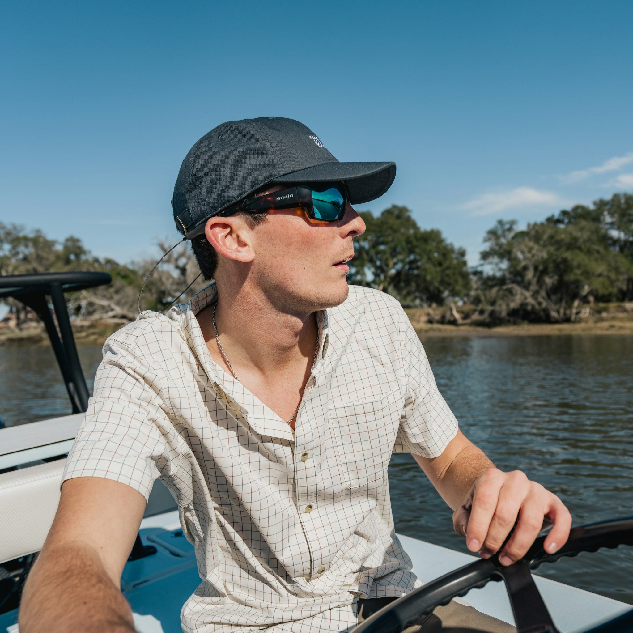 Man driving boat in short sleeve blue and red shirt