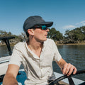 Man driving boat in short sleeve blue and red shirt