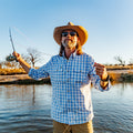 Man casting a fly rod wearing a long sleeve blue button down shirt