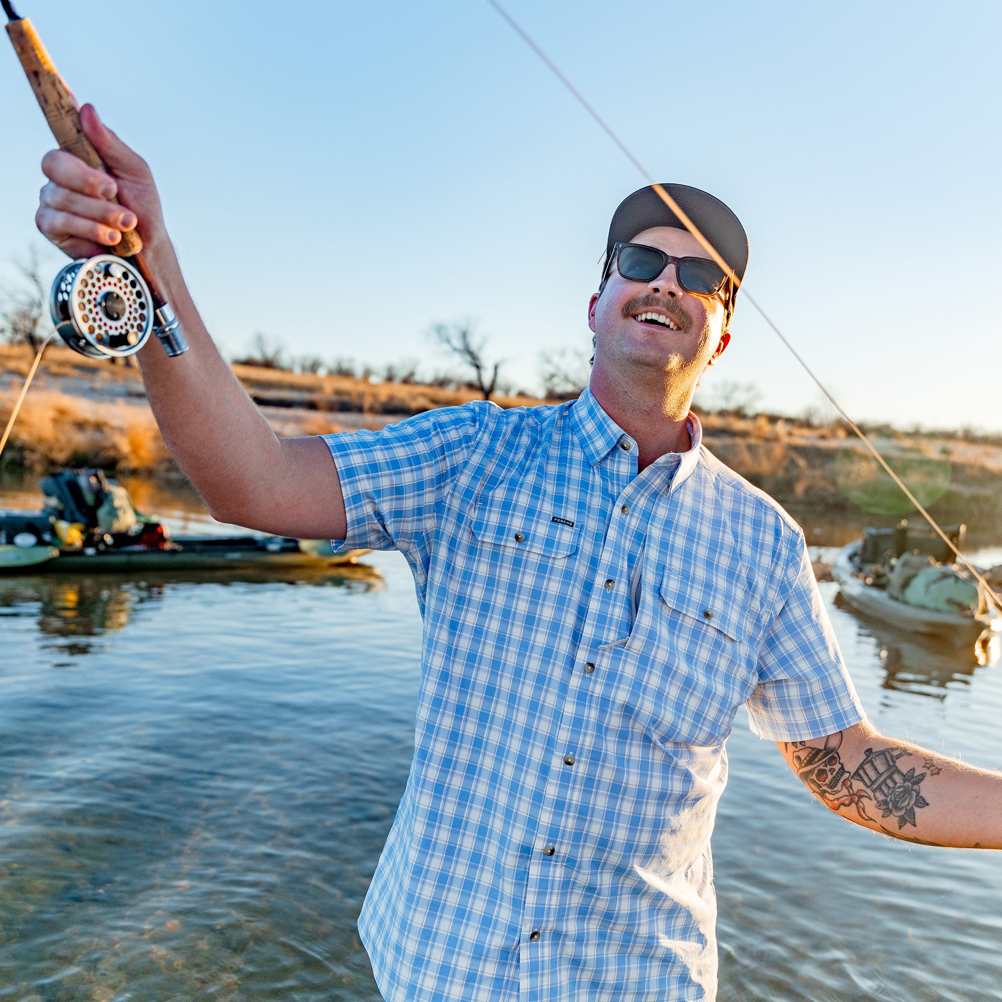 Man casting a a fly rod wearing a blue button down shirt