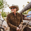 Man tying up horse to gate wearing the brown western corduroy