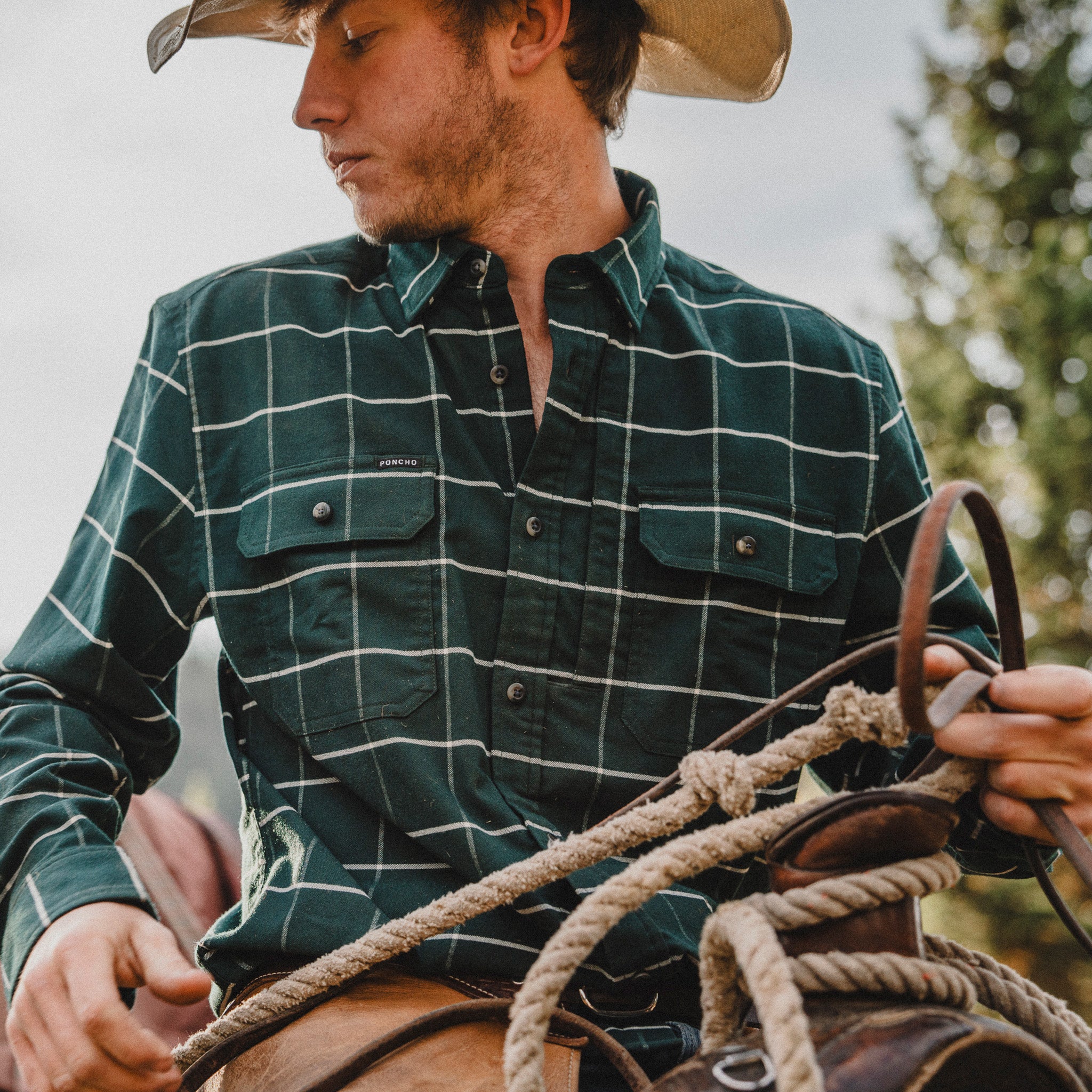 Man riding a horse wearing green plaid flannel 