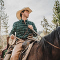 Man riding a horse wearing green flannel