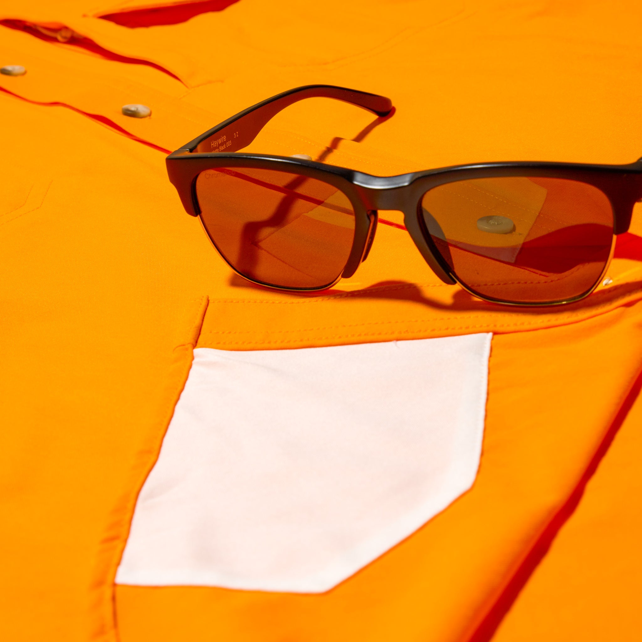 close up photo of sunglass cleaner on bright orange shirt