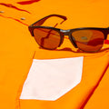 close up photo of sunglass cleaner on bright orange shirt