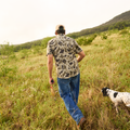 Man walking in field with hunting dog