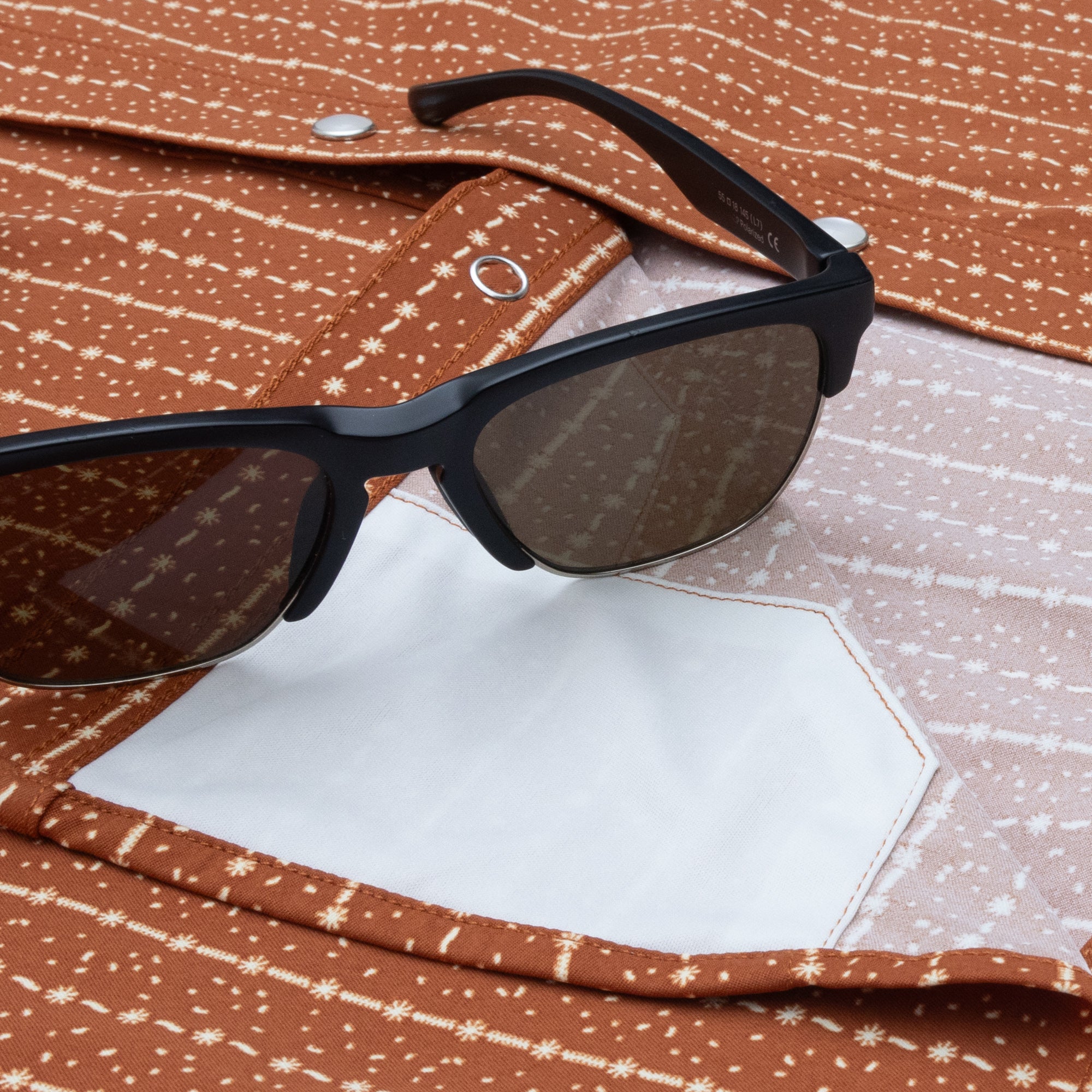 Close up of sunglasses on red shirt with lens cloth