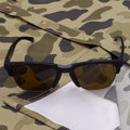 sunglasses on camo shirt with lens cloth