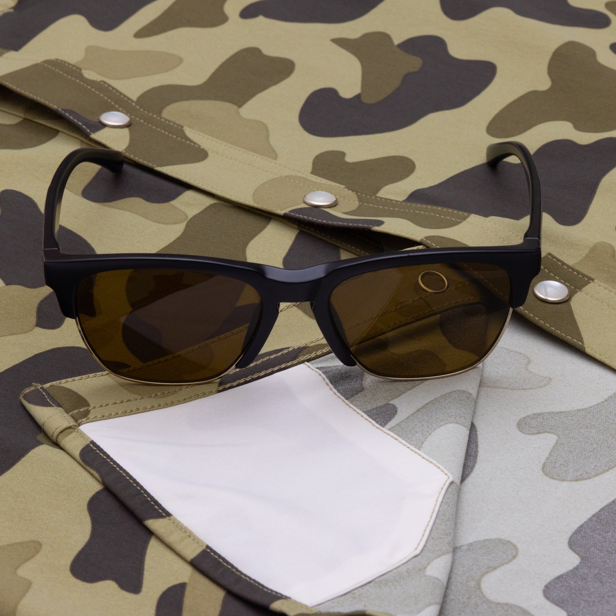 Sunglasses and lens cloth on camo shirt