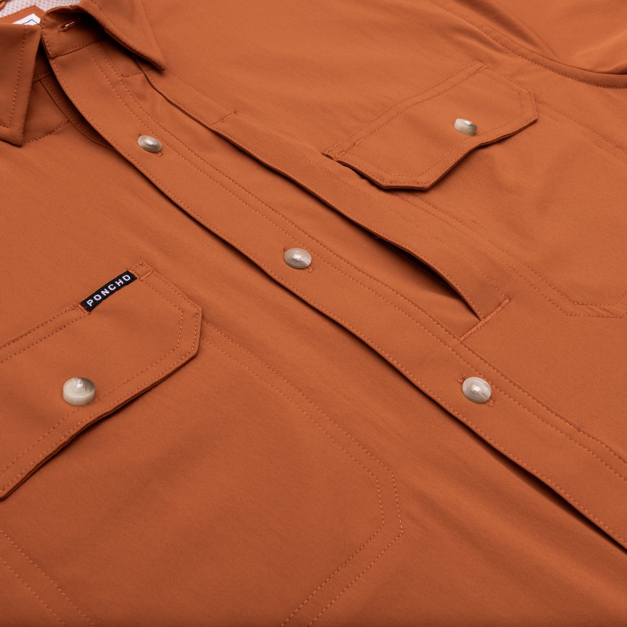 close up of buttons and pockets on burnt orange shirt