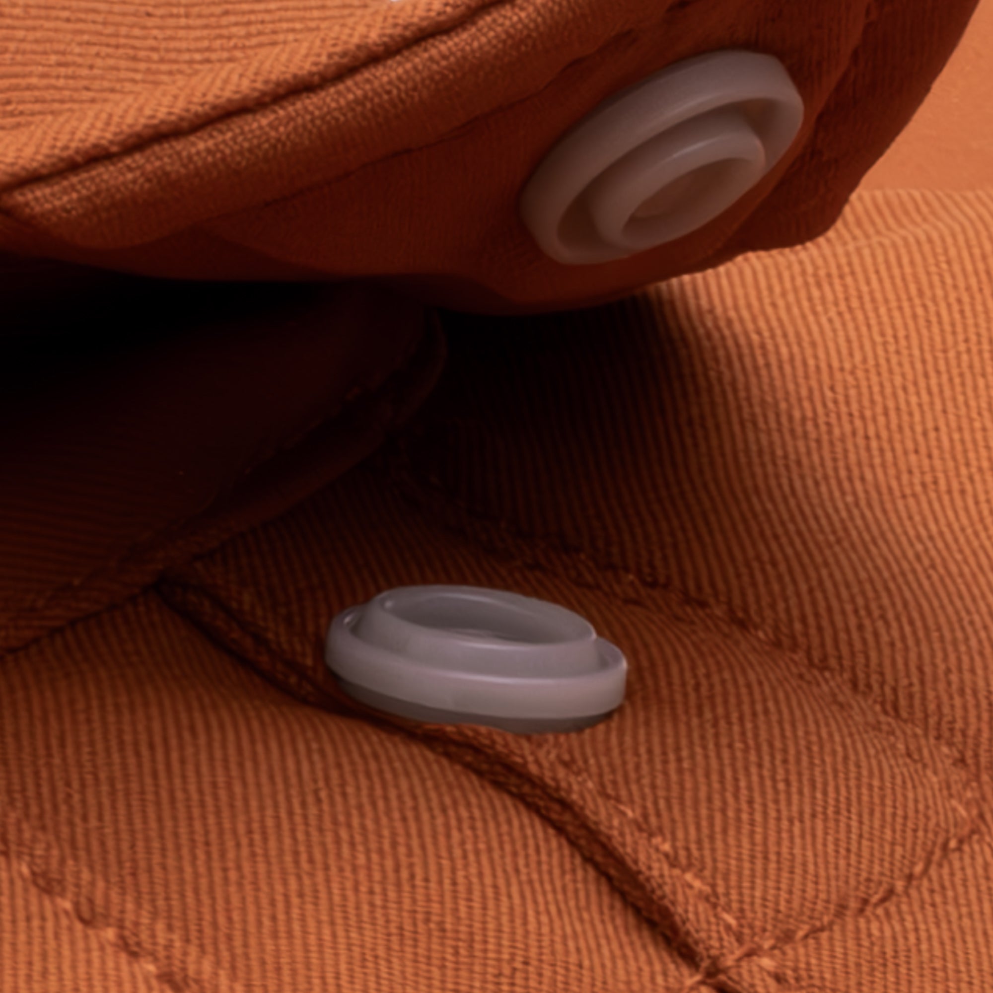 close up photo of snap collar button on burnt orange shirt