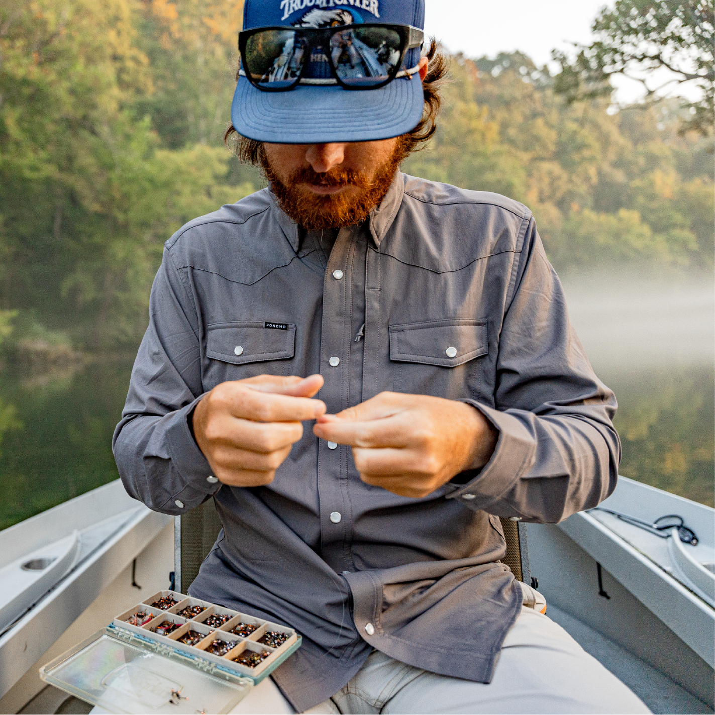 man tying on flies while fly fishing out of a drift boat