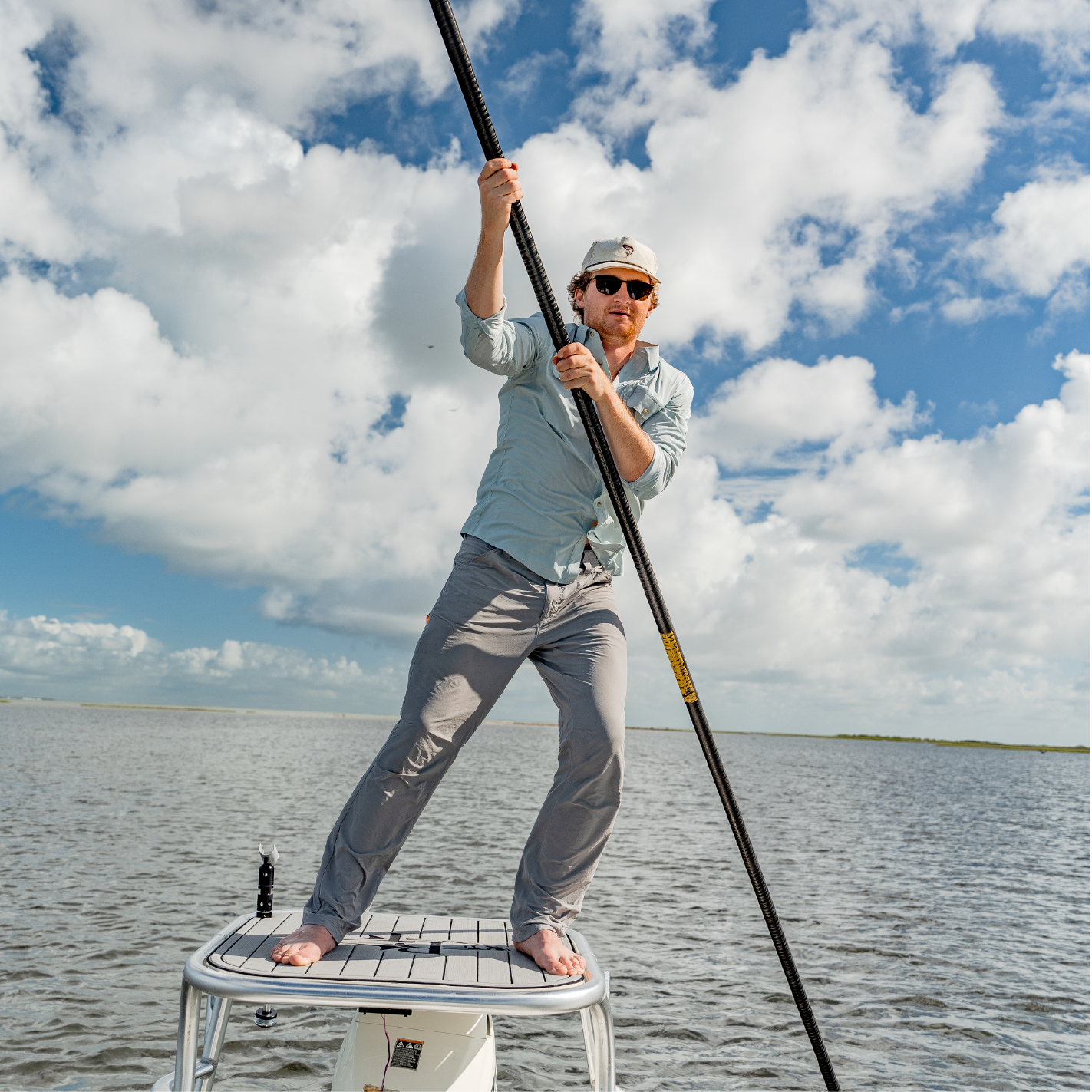 man poling skiff in long sleeve green button up shirt 