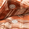 close up of buttons on orange plaid flannel shirt