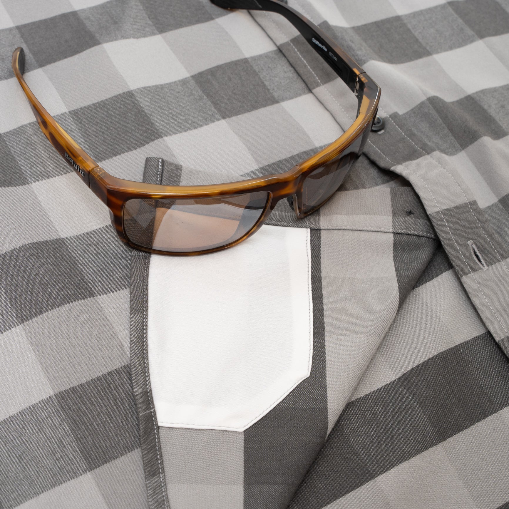 sunglasses on black plaid flannel with hidden sunglass cleaner fabric