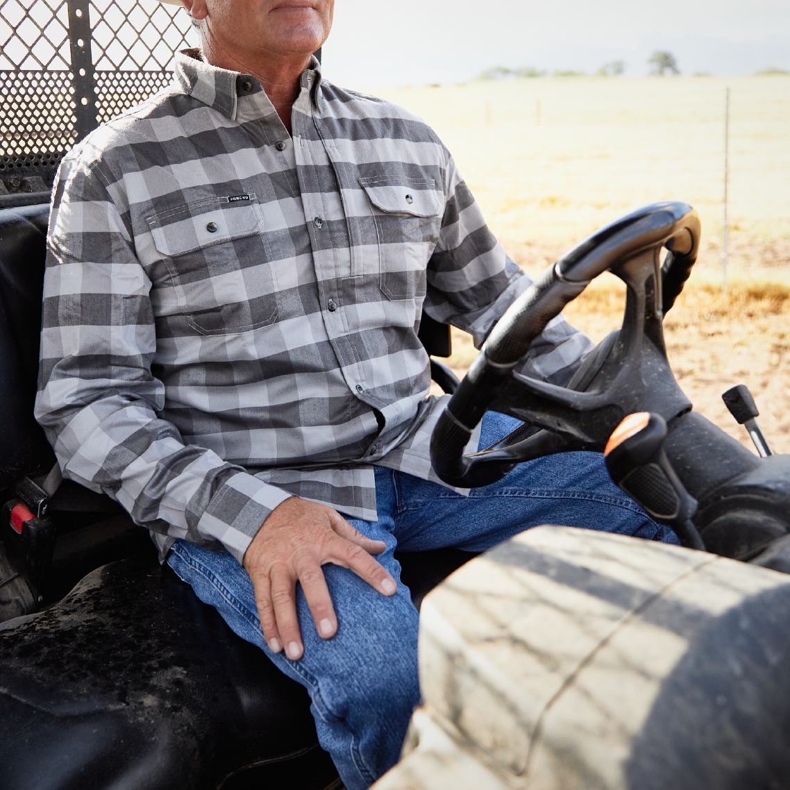 man riding a four wheeler while wearing a black plaid flannel shirt