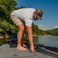 man grabbing fishing poles wearing a green micro grid shirt