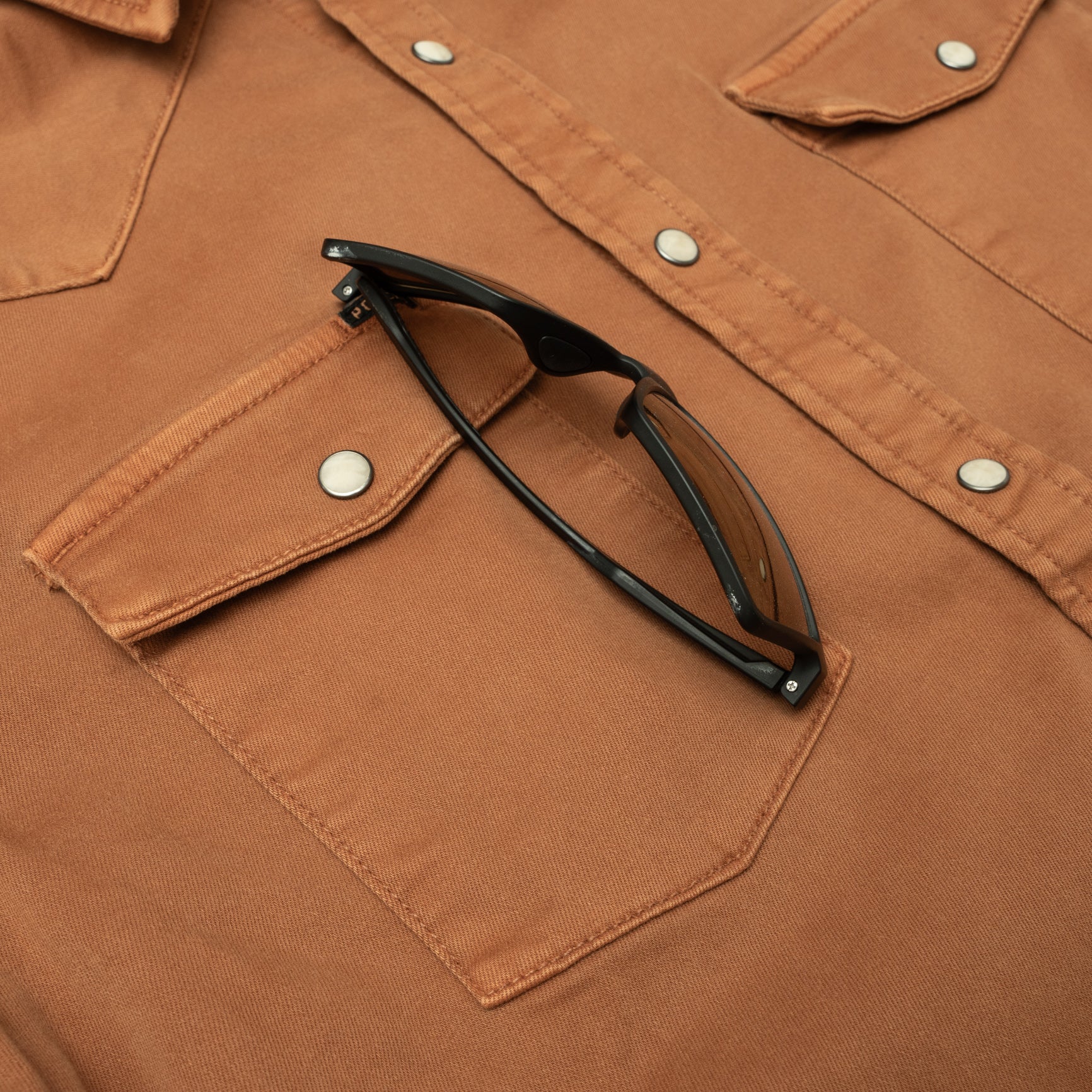 sunglasses in chest pocket of burnt orange denim pearl snap