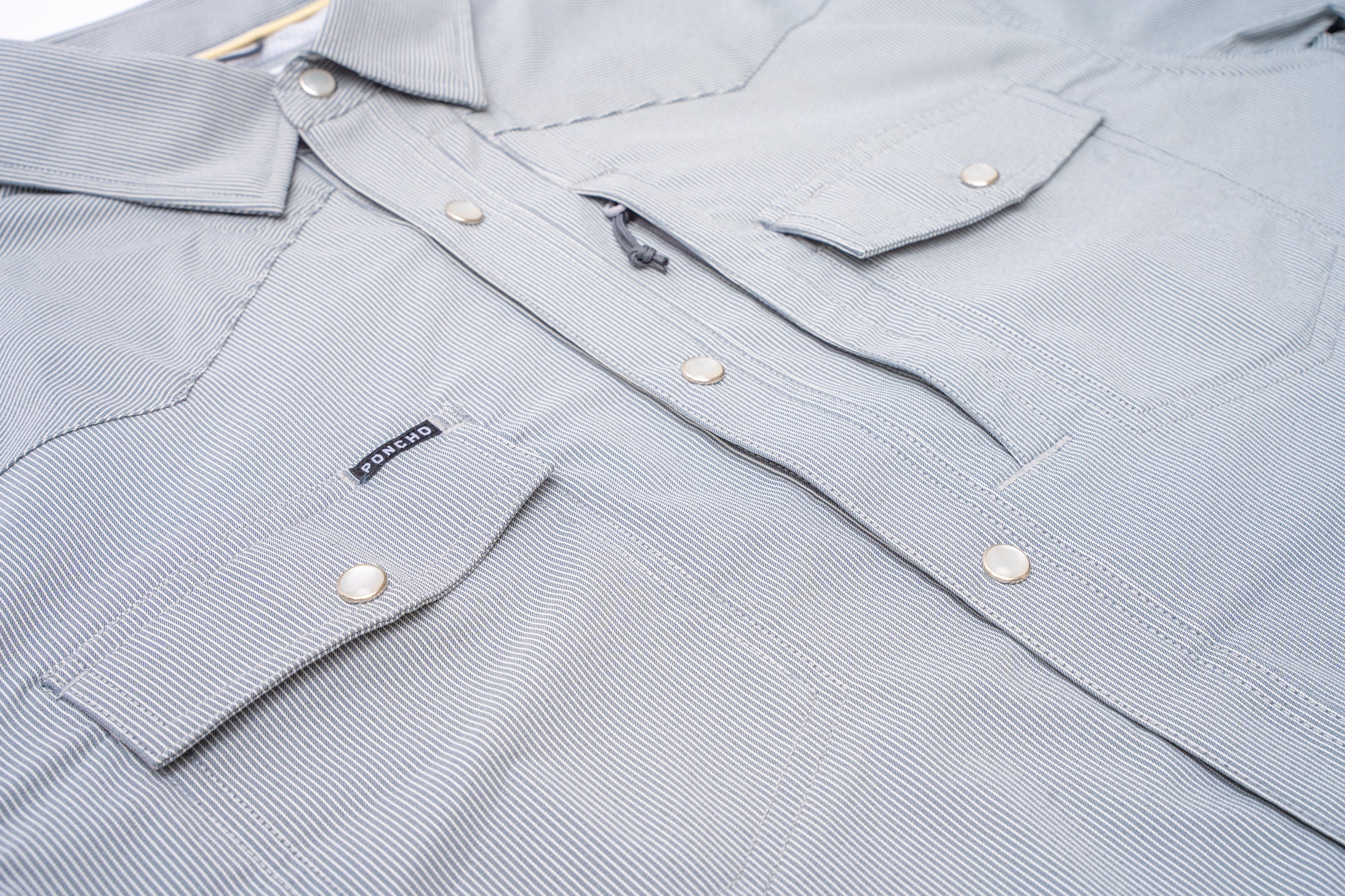 close up of buttons and pockets on slate blue striped shirt