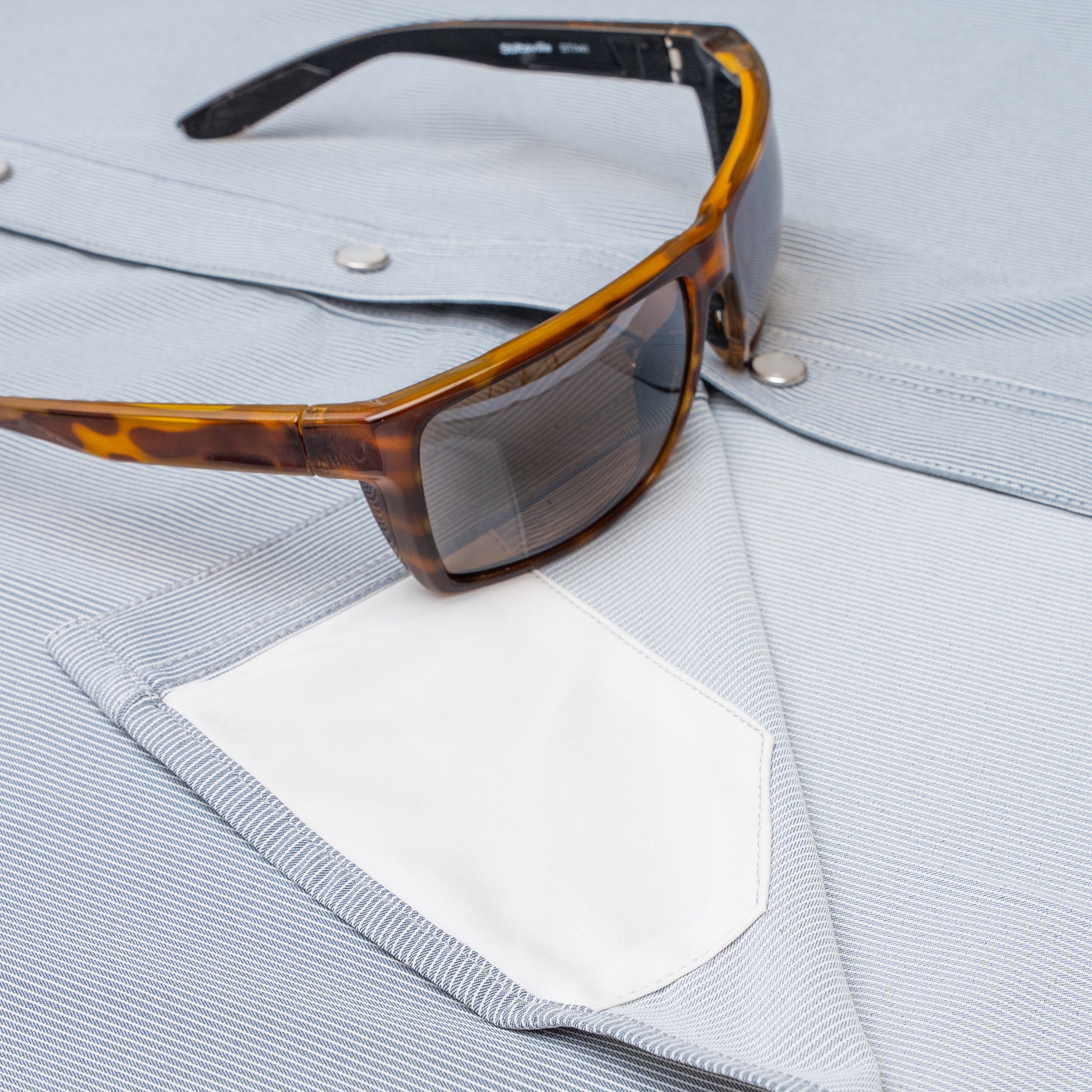 Close up of sunglasses with lens cloth on slate grey shirt