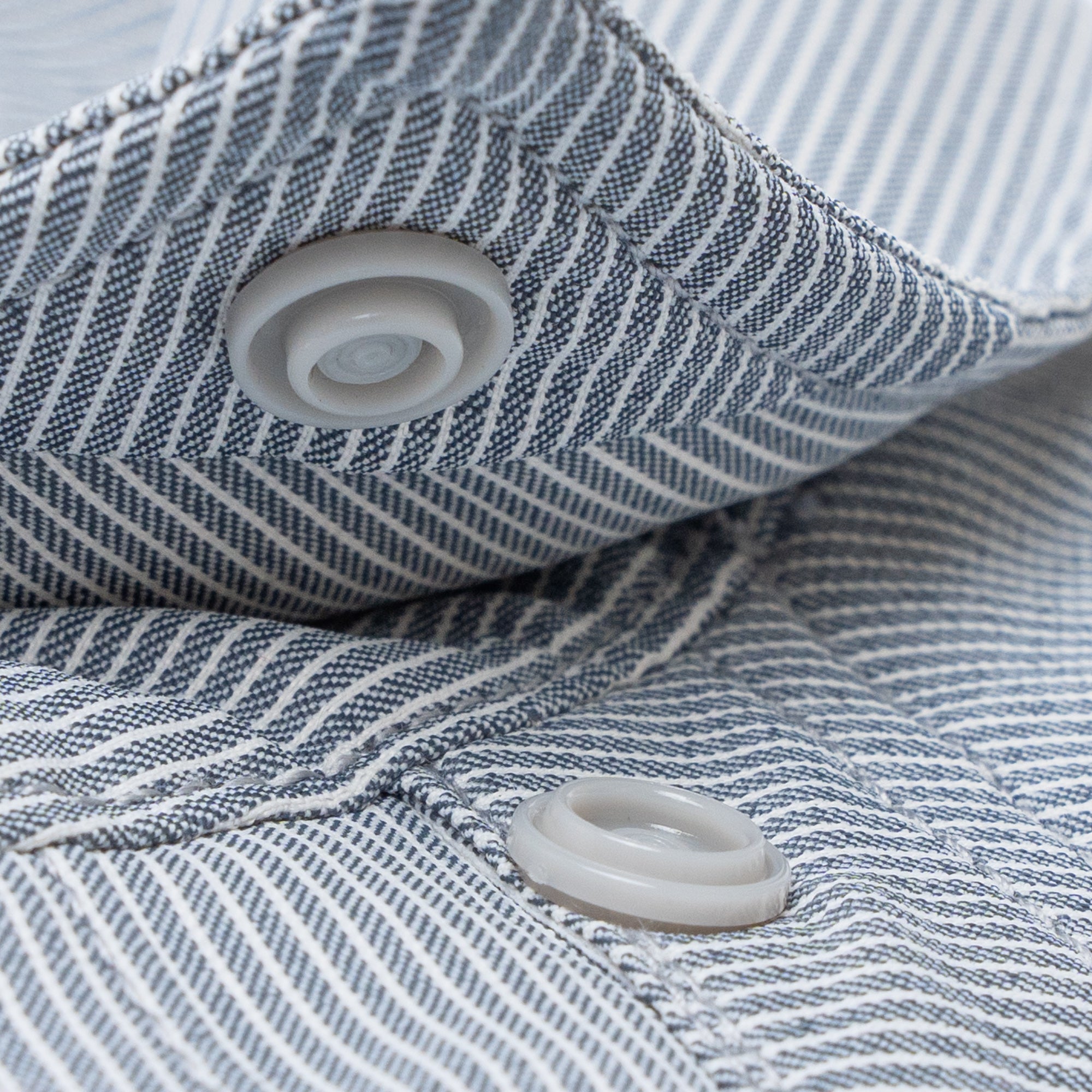 close up photo of snap collar button on striped shirt