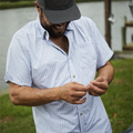 Man wearing grey and blue short sleeve shirt while setting up fishing gear