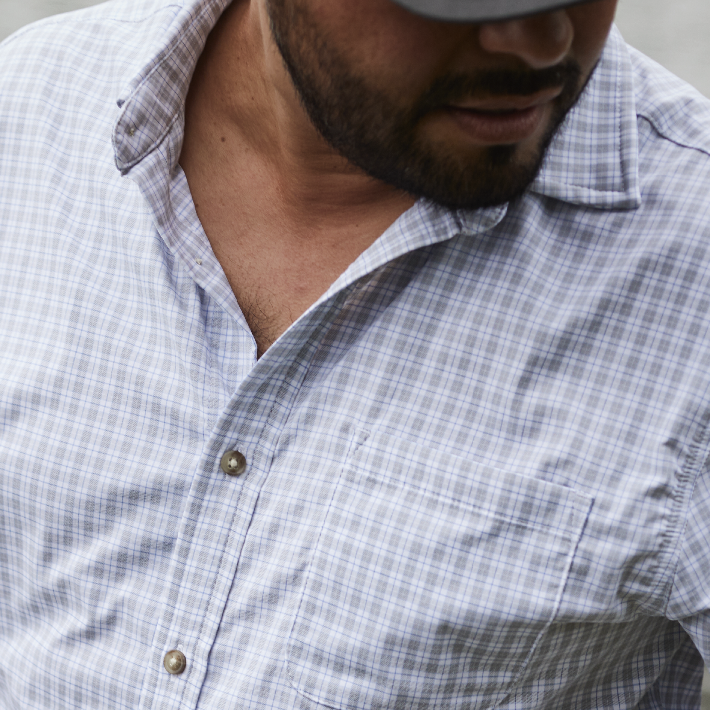 Close up of man wearing a blue and grey plaid button down shirt