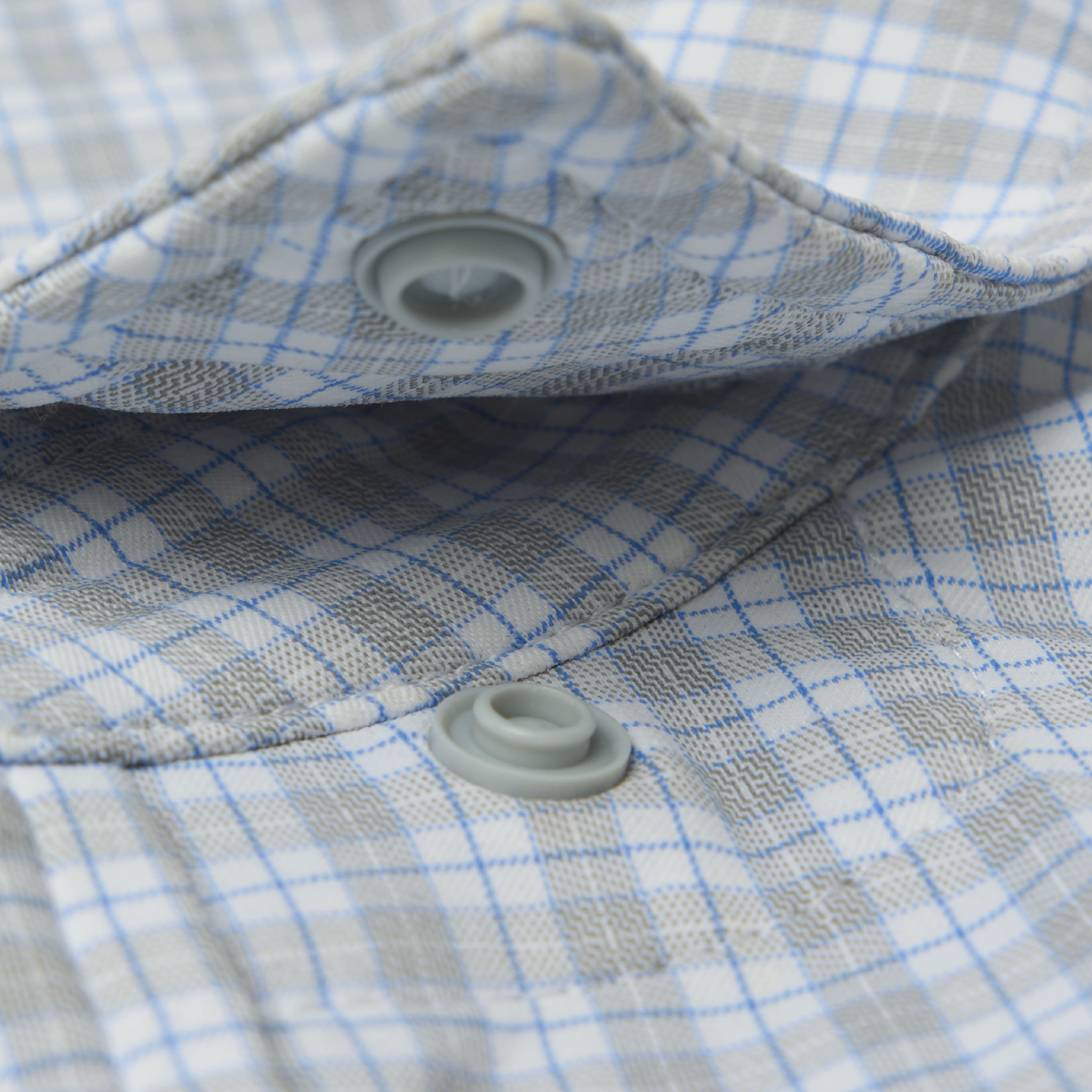 Close up of snap button collar on blue and grey plaid shirt