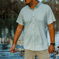 man holding fly rod wearing green microgrid button down shirt