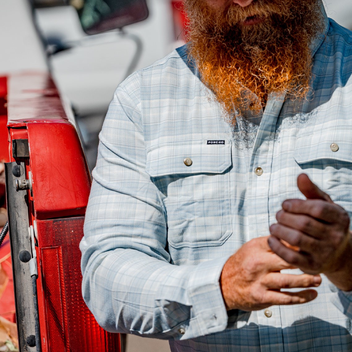 man standing next to a truck wearing the blue plaid flannel with buttons