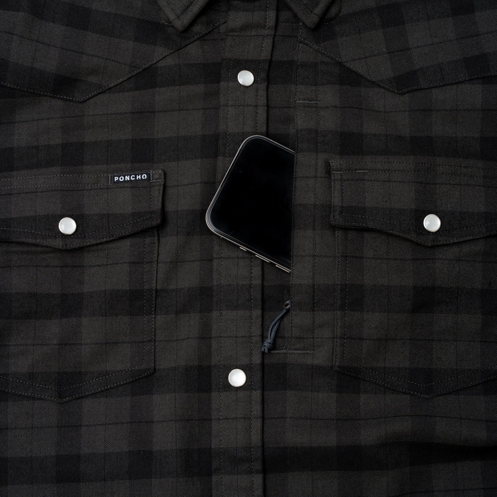 Phone in hidden chest zippered pocket of pearl snap flannel shirt