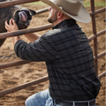 Man working with water buffalo wearing black plaid shirt