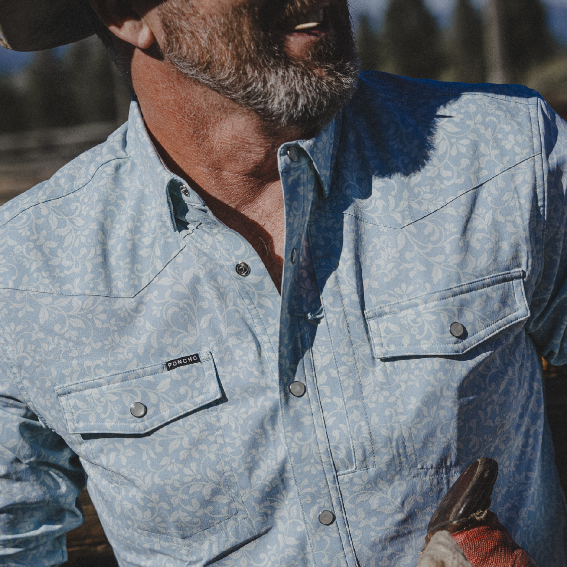 Cowboy wearing blue paisley western shirt in the mountains