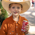 young boy holding a soda wearing the burnt orange short sleeve pearl snap