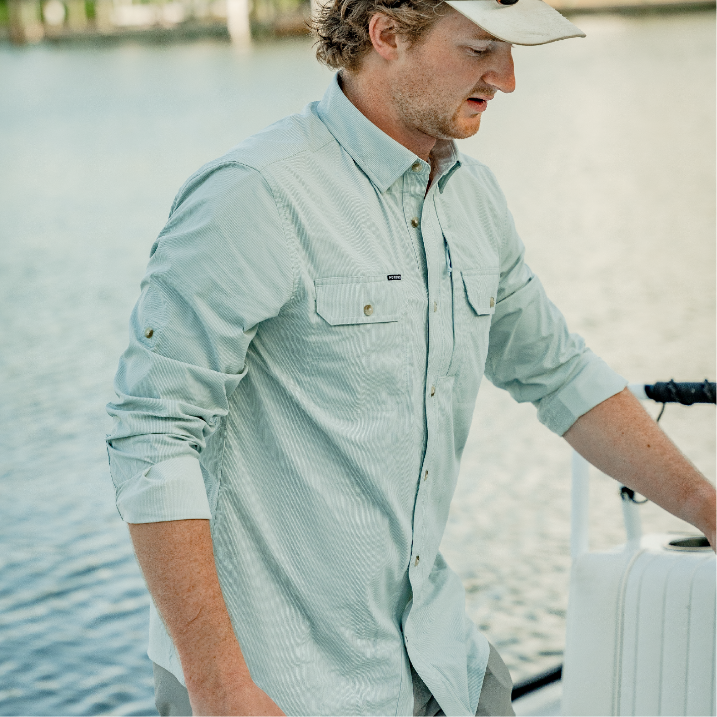 Man on boat wearing green long sleeve button up fishing shirt