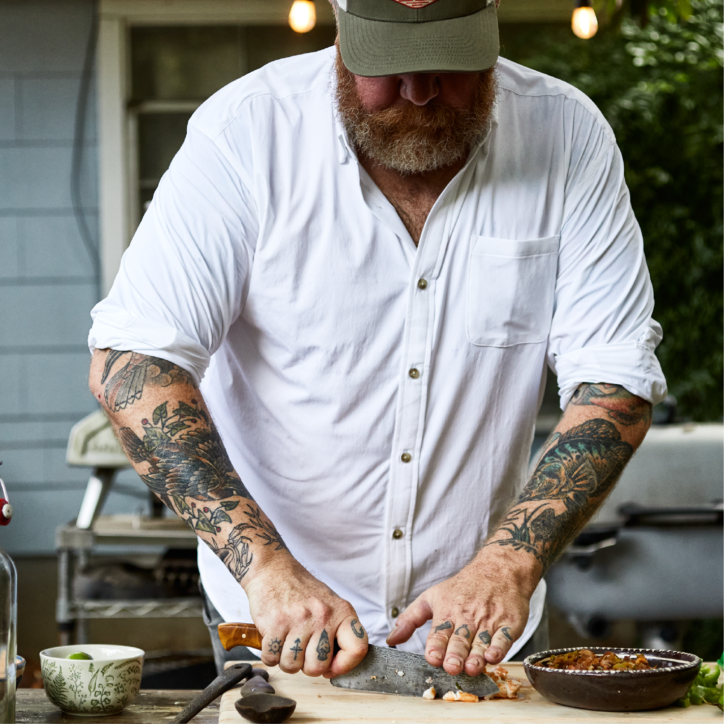 Man chopping ingredients making a meal outside in solid white long sleeve button down